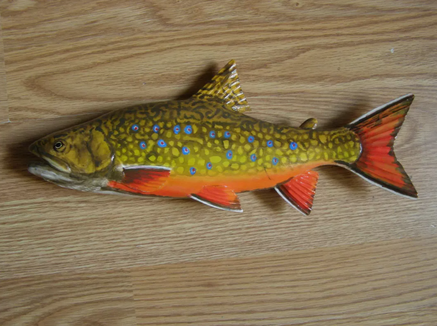 Painted wooden fish carving mounted on a wall board