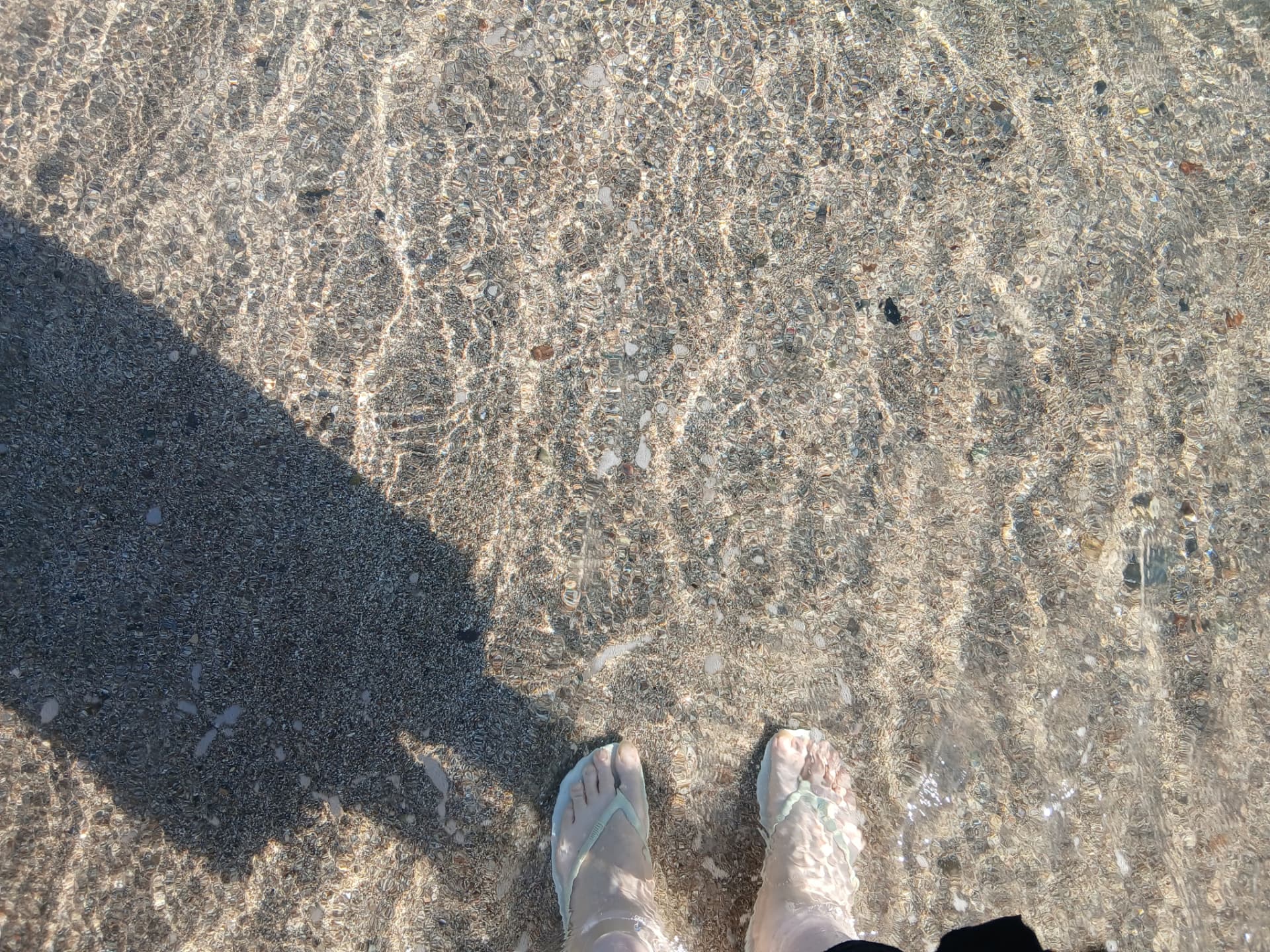 Feet in the warm sand by the shoreline